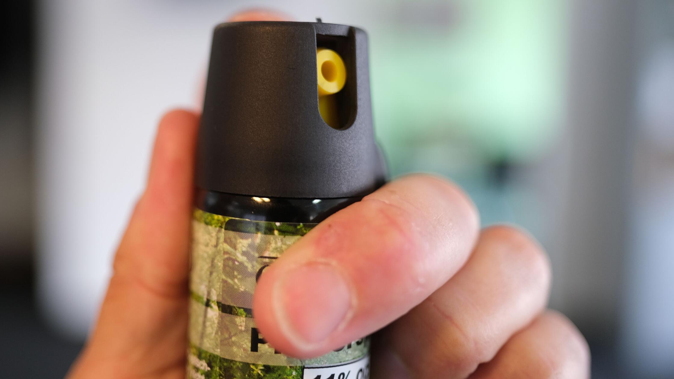 Eine Hand hält eine Kartusche mit Pfefferspray. (z