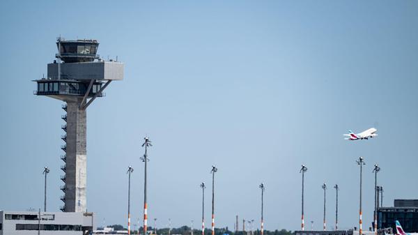 Ein Flugzeug fliegt am Tower des Flughafen Berlin