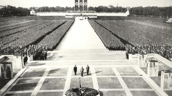 Warum eigentlich Nürnberg? Es waren eher pragmatische Gründe, warum die Nazis ab 1933 jeweils in der ersten Septemberhälfte die zumeist acht Tage dauernden "Reichsparteitage des Deutschen Volkes" hier organisierten: Die zentrale Lage der Stadt und die gute Verkehrsanbindung zählten dazu. Die NSDAP war mit Gauleiter Julius Streicher, einem der größten Judenhasser im Reich, in Franken relativ gut organisiert. Die hiesige Polizei stand dem Nazi-Treiben vergleichsweise wohlwollend gegenüber. Ein ausschlaggebender Punkt für die Wahl Nürnbergs als Austragungsort war auch die bereits vorhandene Luitpoldarena (Im Bild) mit der dazugehörigen Halle. Die Massenveranstaltungen sollten die Menschen für die Ideologie Hitlers begeistern. Erst später wurde die Wahl Nürnbergs damit begründet, dass die Reichsparteitage an die Tradition der Nürnberger Reichstage anknüpfen würden.