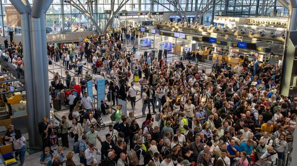 Zahlreiche Reisende stehen in einer Halle auf dem