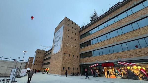 Nach dem Baustopp 2023, als Projektentwickler Gerchgroup in die Insolvenz geraten ist, kommt Ende 2025 wieder Leben auf die Baustelle. Nach rund 16 Jahren, nach der Pleite des fränkischen Versandhändlers, ziehen dort Geschäfte ein. Mittlerweile befinden sich ein Drogerie- sowie ein Supermarkt und ein Discounter in dem Gebäude.