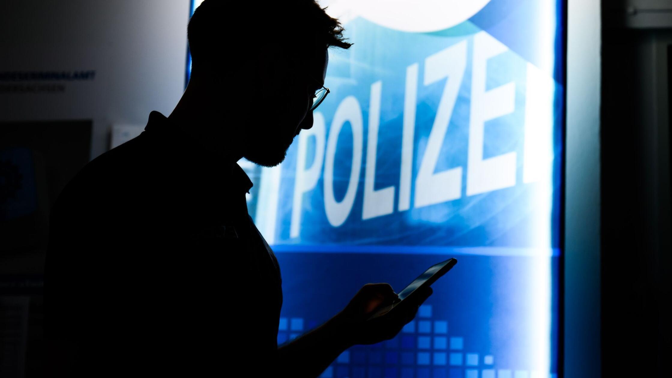 Ein Polizist steht mit einem Smartphone in der Prä