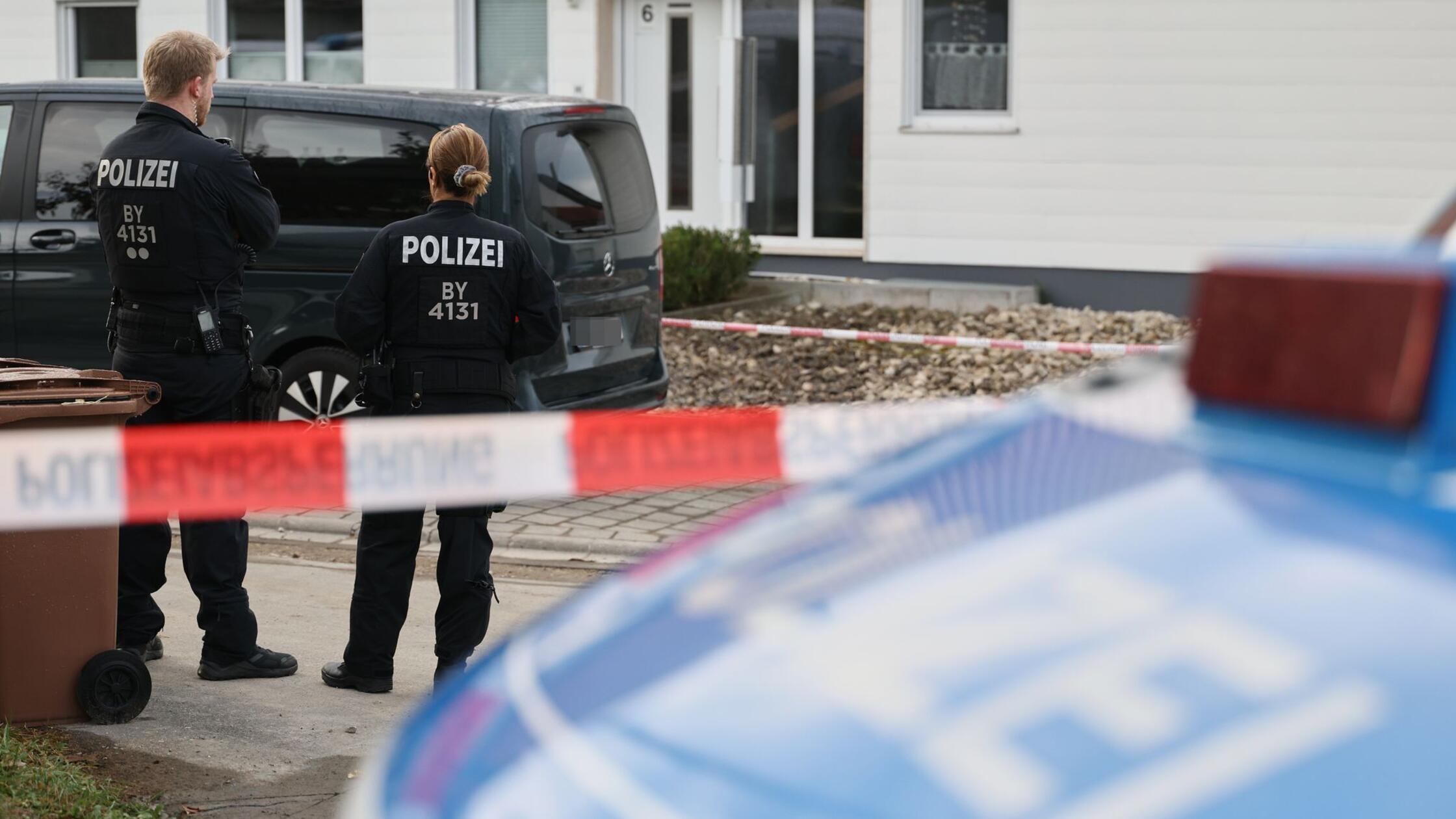 Polizisten stehen an einer Flatterbandabsperrung v