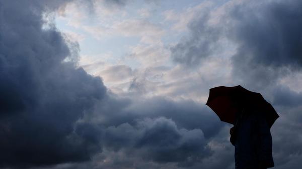 Ein Mann geht mit einem Regenschirm vor aufziehend