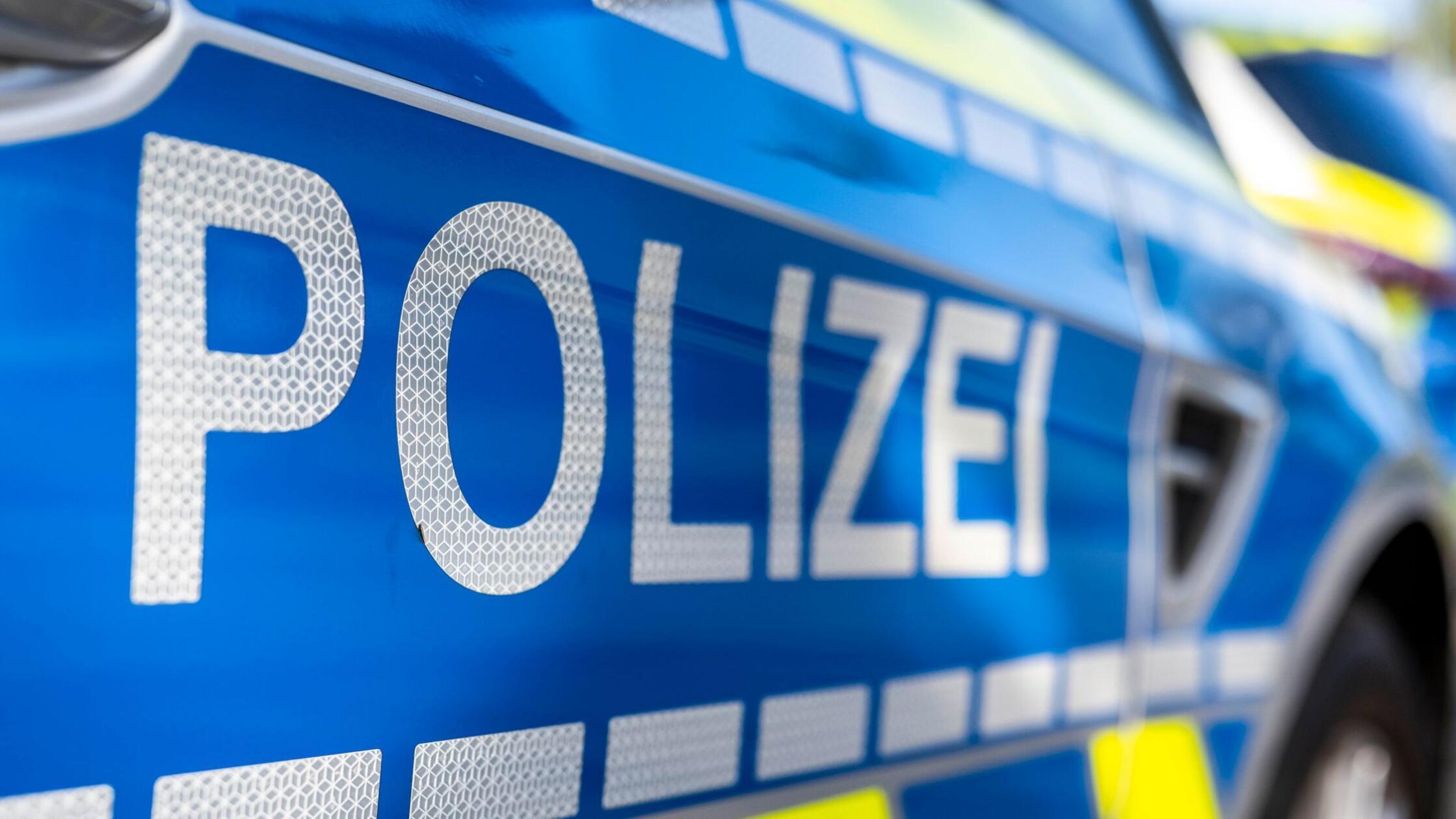 An der Tür von einem Streifenwagen steht der Schri