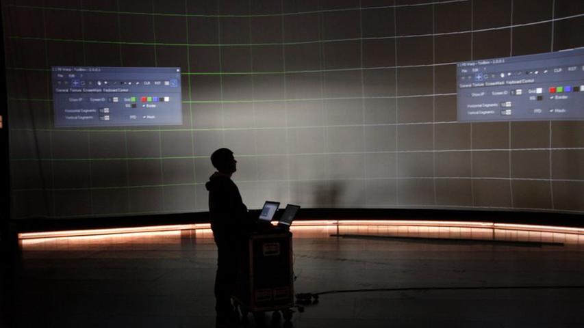Techniker programmieren die große Videoleinwand im Saal.