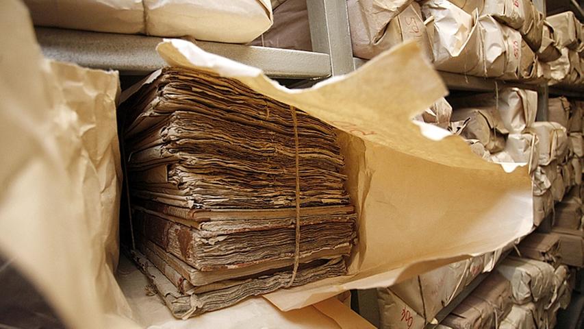 Allein hunderte Urkunden wurden in 44 Holzkisten aufbewahrt. Die Mitarbeiter des Nürnberger Staatsarchivs ziehen die Pappornder und Schriften vorsichtig heraus und begutachten diese.