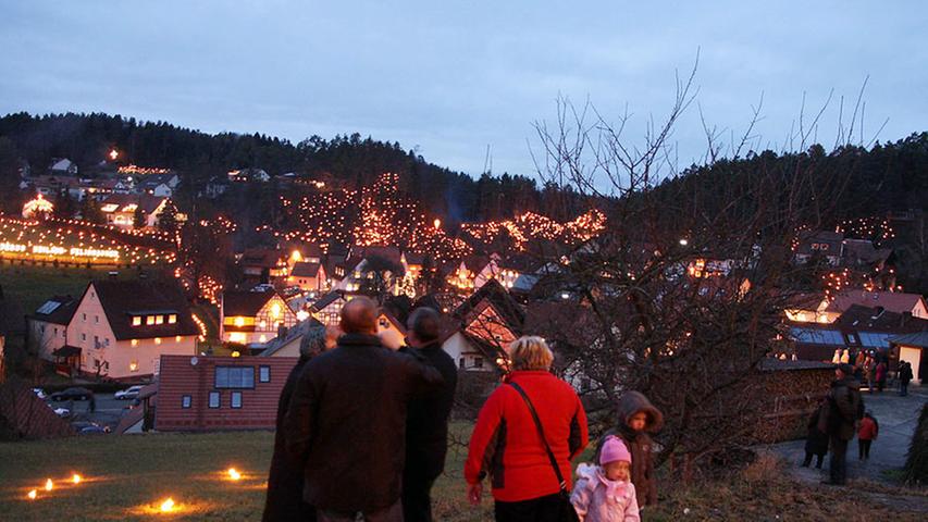 Über Obertrubach in der Fränkischen Schweiz leuchten die Hänge: Die dortige Kirchengemeinde feiert jedes Jahr am 3. Januar den Beschluss der Ewigen Anbetung. Am Abend ziehen die Gläubigen mit einer Lichterprozession durch den Ort.