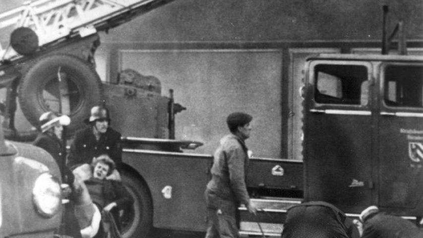Die ersten Opfer werden geborgen: Männer der Feuerwehr und des Roten Kreuzes tragen eine Frau (links im Bild), die aus dem Fenster gesprungen war, zum Krankenwagen.