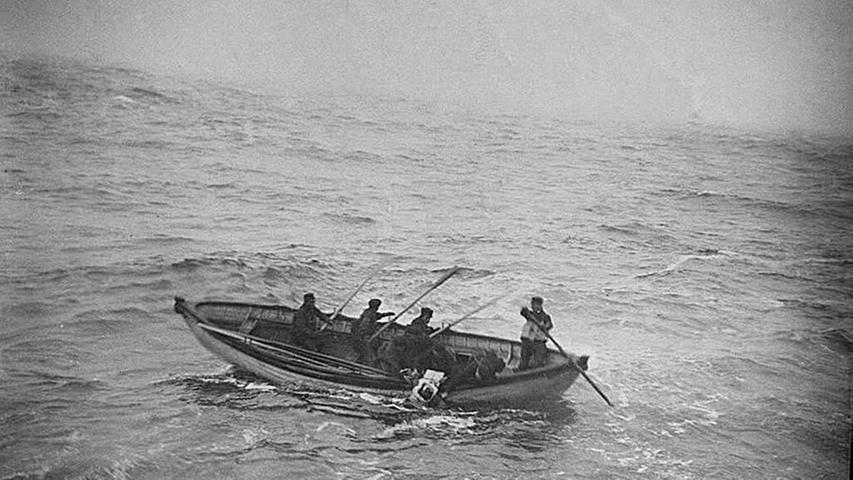 Nachdem die Titanic in zwei Teile zerbrochen war, versank sie in den frühen Morgenstunden des 15. Aprils 1912 im Nordatlantik. Ungefähr 1500 Menschen wurden mit dem Schiff in die Tiefe gerissen, ertranken oder erfroren in dem nur wenige Grad über Null kalten Wasser. Die Menschen, die einen Platz in einem der Rettungsboote ergattern konnten, mussten nach dem Untergang der Titanic ungefähr zwei Stunden auf ihre Rettung warten. Das hier gezeigte Foto wurde von einem Passagier der Carpathia aufgenommen. Der Passagierdampfer war als erstes Schiff an der Unglücksstelle und brachte die überlebenden Passagiere der Titanic nach New York.