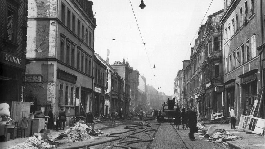 Die Ecke Tafelfeldstraße/Wiesenstraße nach einem Bombenangriff um 1944: Auf den Straßen liegen ausgerollte Feuerwehrschläuche, vor einem ausgebrannten Haus steht ein Löschwagen. Die ausgebombten Nürnberger haben Stühle, Kommoden und anderen noch brauchbaren Hausrat auf dem Bürgersteig zwischengelagert.