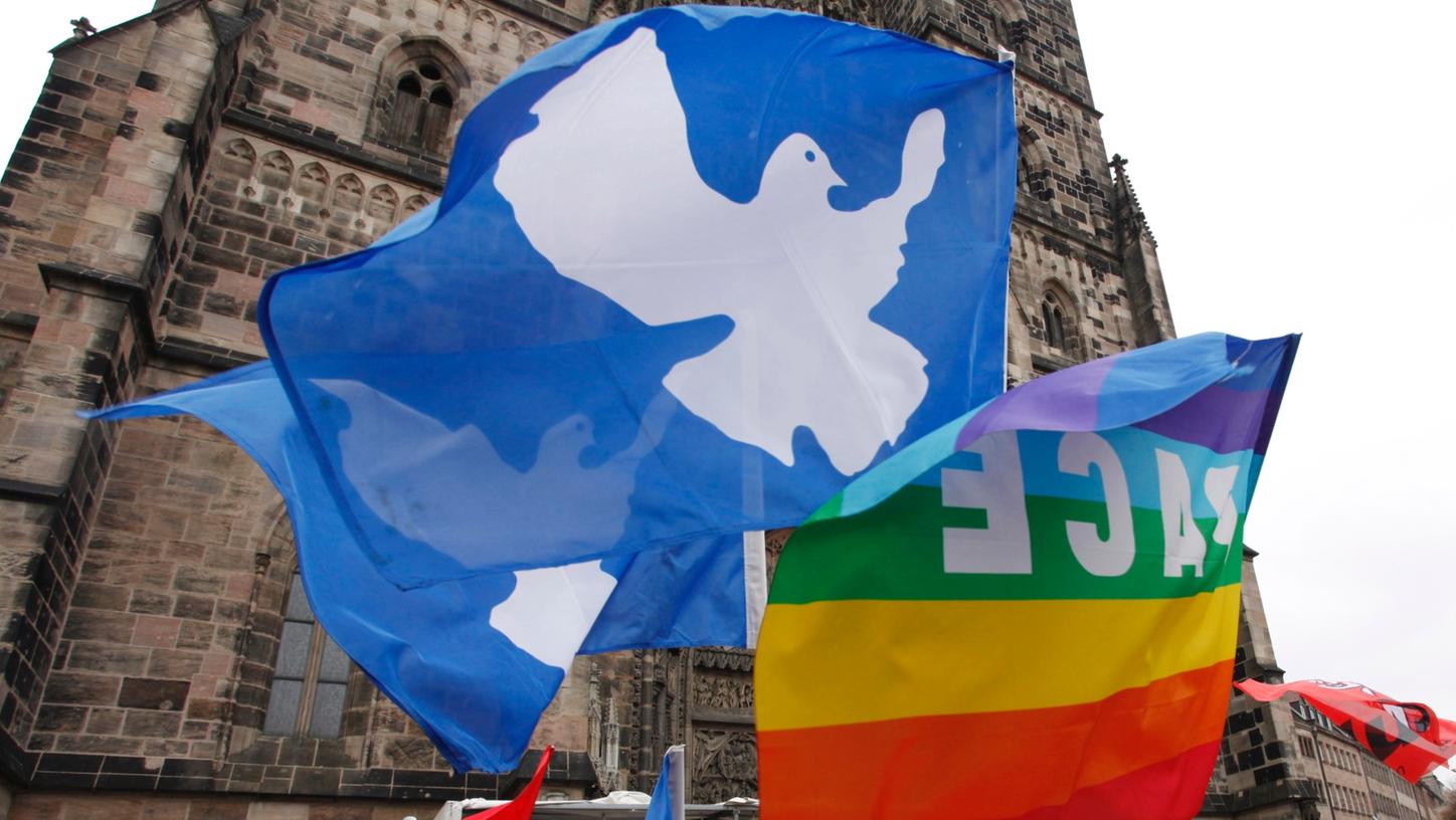 Friedensfahnen wehen am Ostermarsch vor der Nürnberger Lorenzkirche. Weil sie Kriege nicht mitfinanzieren wollen, üben sich einige Nürnberger seit Jahren im Steuer-Boykott.