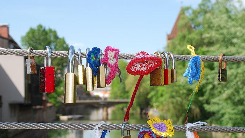 2. Mai: Guerilla-Stricken war gestern, jetzt wird gehäkelt: Unbekannte haben in den vergangenen Tagen die Liebesschlösser auf der Brücke am Cinecittà mit Häkel-Blumen verziert.