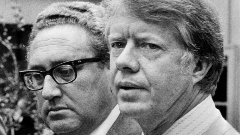 Kissingers Entscheidungen als Außenminister aber sind höchst umstritten. Er steht für eine harte Realpolitik. Kritisiert werden insbesondere seine Rolle beim Putsch in Chile 1973, die Genehmigung der völkerrechtswidrigen indonesischen Invasion in Osttimor, bei der in nur einem Jahr etwa 60.000 Menschen zu Tode kamen, sowie die Ausweitung des Vietnamkriegs und die völkerrechtswidrige Bombardierung Kambodschas, um vietnamesische Nachschubrouten zu zerstören. Unter Jimmy Carter (rechts), der 1977 Präsident der USA wird, kann Kissinger seinen Außenminister-Posten nicht mehr behaupten und scheidet weitestgehend aus der aktiven Politik aus.