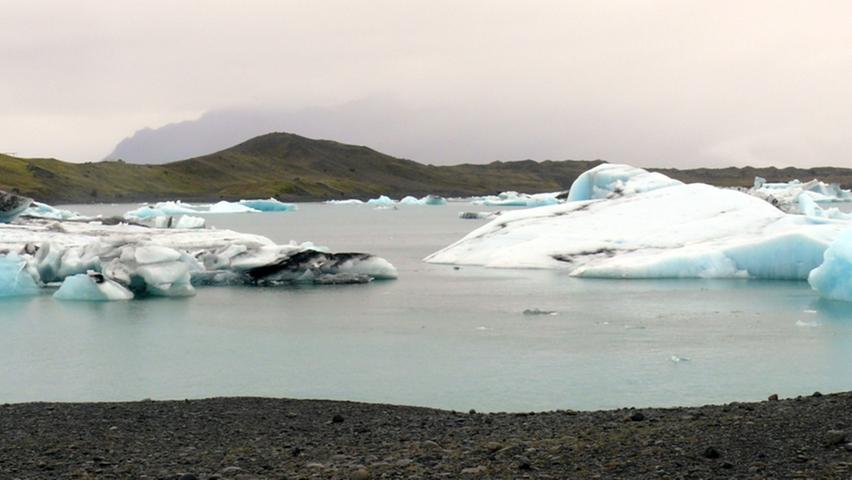 Kleinere und größere Eisberge im Gletschersee des Vatnajökull leuchten in einem fast unnatürlichen Hellblau.