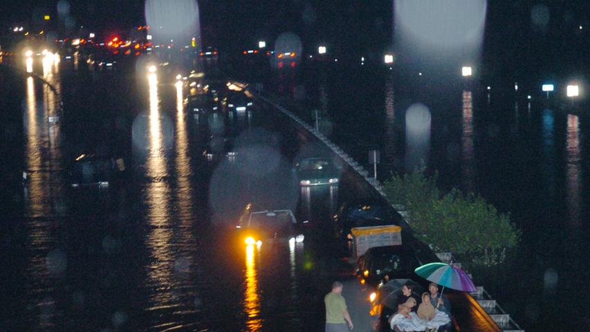 Diese junge Familie brachte sich auf der Kühlerhaube ihres Autos in Sicherheit: Ob der Regenschirm den Wassermassen standhielt?