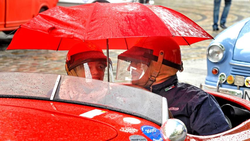 Not macht erfinderisch: Weil diesem Oldtimer das Dach fehlte, mussten sich die Besitzer des Gefährts mit einem Regenschirm schützen. Natürlich in rot, passend zur Wagenfarbe.