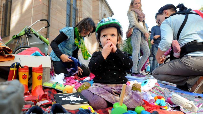 Dieses Mädchen setzte sich mitten rein in die bunte Auswahl an Kindersachen. Der skeptische Blick verrät jedoch: die Kleine gibt ihre Spielsachen nur ungern her.