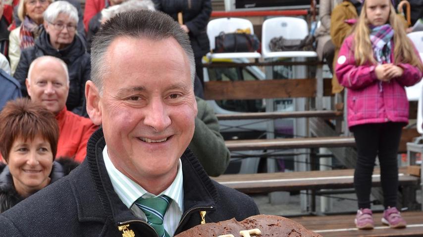 Fürths Oberbürgermeister Thomas Jung hält am Rande des Erntedankfestzuges einen überdimensionalen Laib Brot hoch.