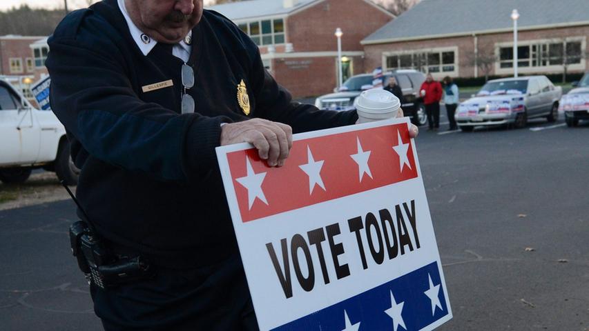 Ein Polizist steckt ein Wahlschild vor einem anderen Wahllokal in Wrentham, Massachusetts, in den Boden.