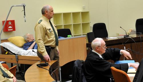 Umringt von Polizisten liegt der Angeklagte Rudolf U. bei der Fortsetzung des Prozesses wegen Mordes an einem jungem Staatsanwalt in Dachau in einem Krankenbett im Gerichtssaal. Umringt von Polizisten liegt der Angeklagte Rudolf U. bei der Fortsetzung des Prozesses wegen Mordes an einem jungem Staatsanwalt in Dachau in einem Krankenbett im Gerichtssaal.