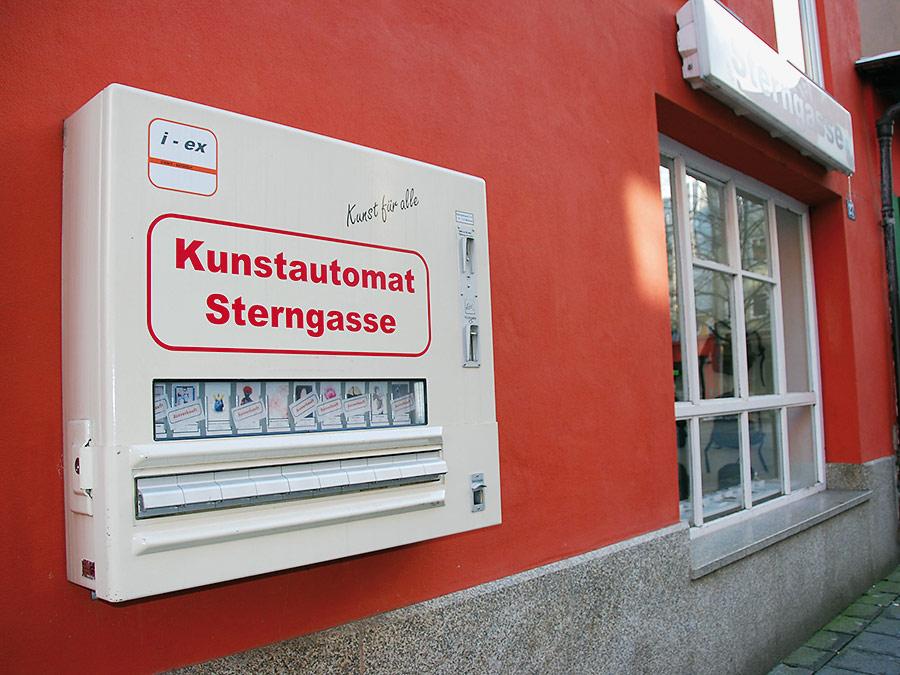 Seit 2010 bereichert das Künstlerpaar Winfried Baumann und Anna Bien die Hintere Sterngasse um ein einzigartiges Kultobjekt: den Kunstautomaten, der die Kunstraum-Sterngasse-Galerie schon in der 35. Staffel ergänzt. Das Motto lautet "Kunst für alle." Für fünf Euro ist man dabei und findet oft ein ganz besonders originelles Geschenk - vorausgesetzt, man ist schnell genug. Die zigarettenschachtel-großen Päckchen sind nämlich regelmäßig vergriffen.