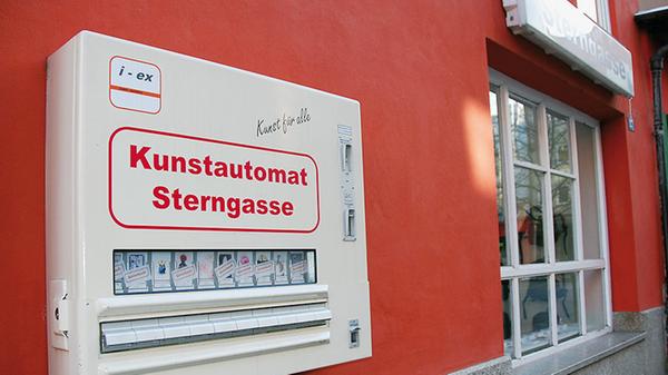 Seit 2010 bereichert das Künstlerpaar Winfried Baumann und Anna Bien die Hintere Sterngasse um ein einzigartiges Kultobjekt: den Kunstautomaten, der die Kunstraum-Sterngasse-Galerie schon in der 35. Staffel ergänzt. Das Motto lautet "Kunst für alle." Für fünf Euro ist man dabei und findet oft ein ganz besonders originelles Geschenk - vorausgesetzt, man ist schnell genug. Die zigarettenschachtel-großen Päckchen sind nämlich regelmäßig vergriffen.