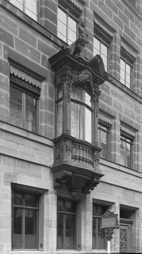Die Stadt Nürnberg ist vor allem für ihre vielen Chörlein bekannt. Dies sind Erkerausbauten, die meist aus Holz oder Stein sind und sich im ersten Obergeschoss eines Hauses befinden. Als Beispiel hier ein Rokoko-Chörlein an einem Wohnhaus in der Karolinenstraße 30. Das Foto entstand 1910.