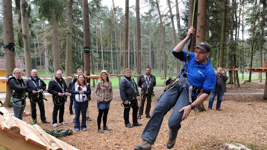 So wird's gemacht. Die Initiatoren des Kletterparkes zeigen den Besuchern, wie sie sich sichern und dann von Baum zu Baum schwingen können.
