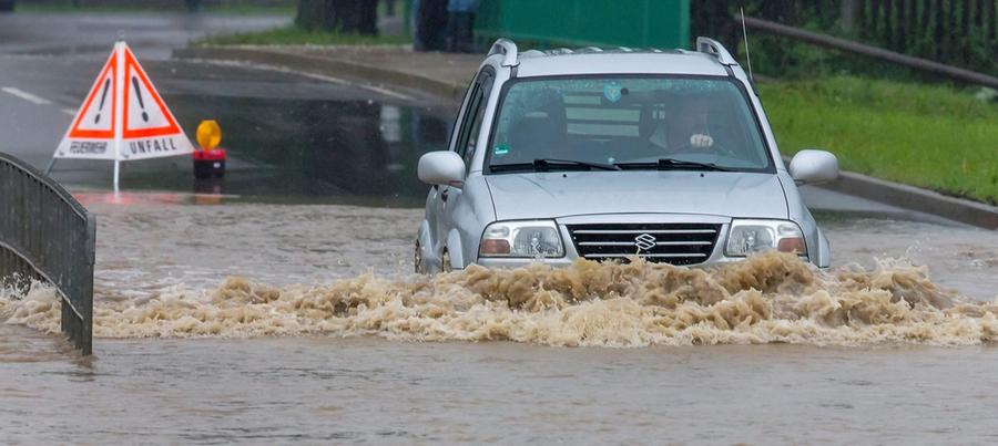 Ein Auto fährt am in Kirchheim (Thüringen) durch das Wasser auf einer gesperrten Strasse. Die Wipfra ist hier über die Ufer getreten.