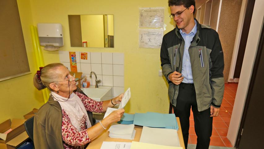 ...Und auch der SPD-Direktkandidat Philipp Dees zeigt in der Mönauschule Präsenz. Wahlhelferin Hella Poupoules (li.) händigt ihm seine Wahlunterlagen aus.