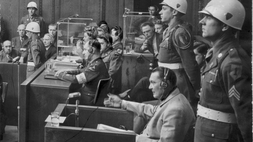 Der Hauptkriegsverbrecher Hermann Göring auf dem Zeugenstuhl, flankiert von MP-Soldaten. Er wurde am Ende des Prozesses zum Tode verurteilt, schaffte es aber einige Stunden vor dem Tod durch den Strang, sich mit einer Zyankalikapsel selbst zu töten.