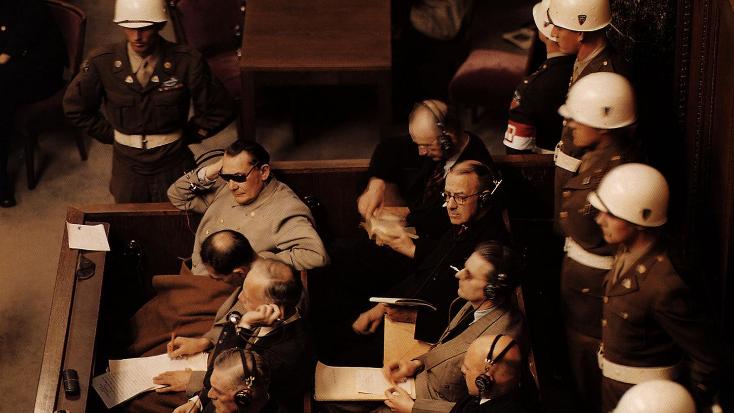 Einer der Hauptangeklagten bei den Nürnberger Prozessen war der frühere Reichsmarschall Hermann Göring (mit Sonnenbrille). Gleich neben ihm der einstige Stellvertreter des Führers, Rudolf Heß. Göring schützt seine Augen vor den 22 Deckenstrahlern, die den Saal für die Prozess-Filmaufnahmen ausleuchteten. 