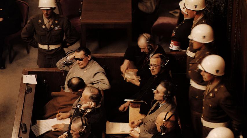 Der Mann mit der Sonnenbrille ist der frühere Reichsmarschall Hermann Göring, gleich neben ihm der einstige Stellvertreter des Führers, Rudolf Heß. Göring schützt seine Augen vor den 22 Deckenstrahlern, die den Saal für die Prozess-Filmaufnahmen ausleuchteten.