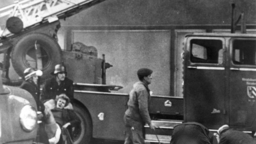 Die ersten Opfer werden geborgen: Männer der Feuerwehr und des Roten Kreuzes tragen eine Frau (links im Bild), die aus dem Fenster gesprungen war, zum Krankenwagen. Zum Artikel: Falsches Handeln in Todesangst