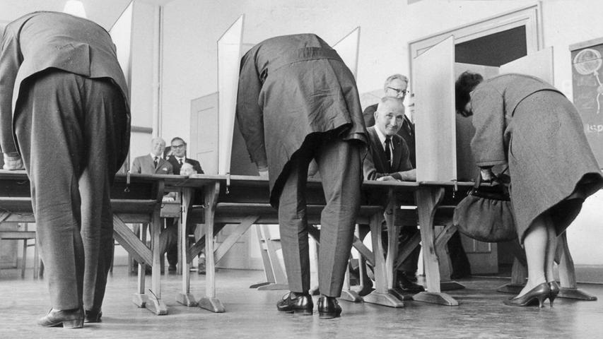 Blick hinter die Wahlzellen: auf niederen Bänken machen Männer und Frauen ihr Kreuzchen.  Zum Artikel: Zwei Kandidaten im Wahllokal 13