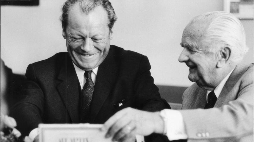 Bei seinem Nürnberger Aufenthalt im Oktober 1971 besuchte der Bundeskanzler die  Redaktion der Nürnberger Nachrichten. Herausgeber Joseph E. Drexel begrüßt hier Willy Brandt, der sich offenbar sehr über ein Gastgeschenk freut.