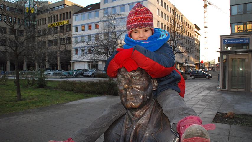 Die kleine Mima klettert auf der Statue am Willy Brandt Platz herum, nachdem ihre Mutter anlässlich Willy Brandts Geburtstag Blumen in dessen Hand gelegt hat.
