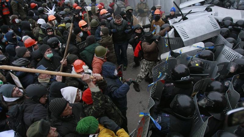 Hunderte mit Holzknüppeln ausgerüstete und mit Masken vermummte Oppositionelle wollten eine Polizeiabsperrung durchbrechen...