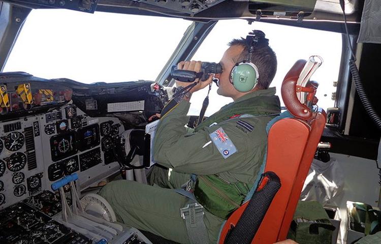 Ein Pilot der australischen Luftwaffe hält Ausschau nach der vermissten Passagiermaschine des Flugs MH370. Laut dem US-Sender NBC vom 19. März war eine Kursänderung des Flugzeuges im Bordcomputer eingestellt, noch ehe sich das Cockpit abgemeldet hatte.