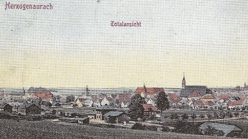 Die historische Ansicht von Herzogenaurach zeigt in der Bildmitte das Schloss, also das jetztige Rathaus, rechts davon die Pfarrkirche St. Magdalena. Im Vordergrund ist die Bahnhofstraße zu sehen. Links befindet sich das heutige Areal von Adidas und Schaeffler.