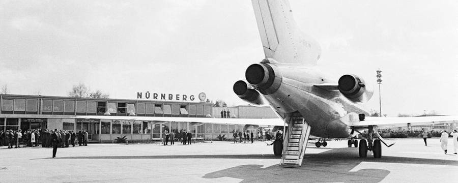 Die neueste Mittelstreckenmaschine der Lufthansa – eine Boeing 727 – wurde gestern auf dem Nürnberger Flughafen vorgestellt – Der „Europa-Jet“, der eine Höchstgeschwindigkeit von 950 Stundenkilometern erreicht, wird bald auf den Strecken nach Madrid, Barcelona, Athen, Beirut und Istanbul eingesetzt. Seine Eigenheit: die Triebwerke befinden sich hinten, wie unser Bild zeigt. Geräuscharmut, Bequemlichkeit in der Kabine und die Fähigkeit, mit kurzen Start- und Landebahnen auszukommen, wurden als die besonderen Vorteile dieses Typs herausgestellt. Die Lufthansa hat, wie betont wurde, eigens länger auf Düsenflugzeuge für ihren Europaverkehr gewartet, um das modernste Flugzeug der Boeing-Werke einsetzen zu können. Die Maschine, die gestern früh in München auf den Namen „Augsburg“ getauft wurde, ist das erste von zwölf Flugzeugen, die von der deutschen Luftverkehrsgesellschaft in Dienst gestellt werden.  Hier geht es zum Artikel: "Ein Glas Sekt über den Wolken"