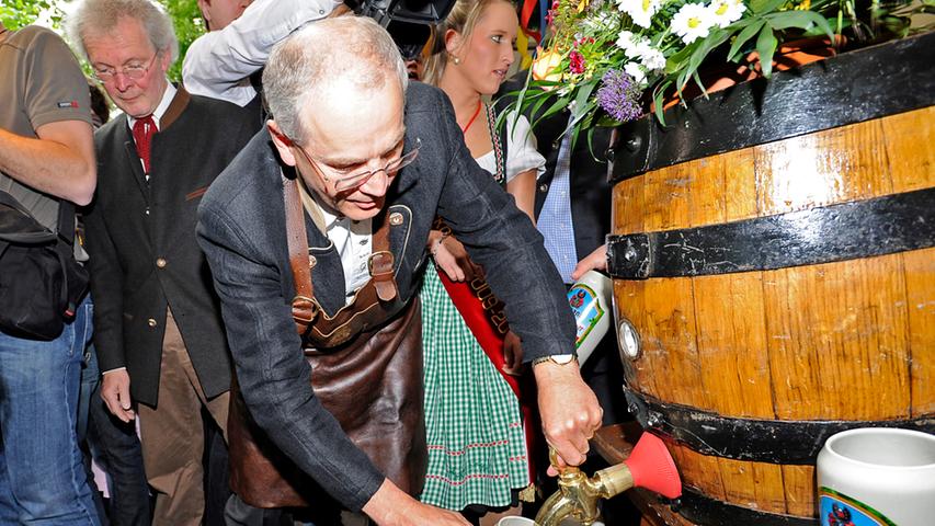 Unter den Augen von Innenminister Joachim Herrmann braucht Siegfried Balleis wieder die obligatorischen fünf Schläge, bis das Bier aus dem Fass fließt. Trotz Nieselregen drängen sich wieder hunderte Menschen, um ein Freibier abzustauben.