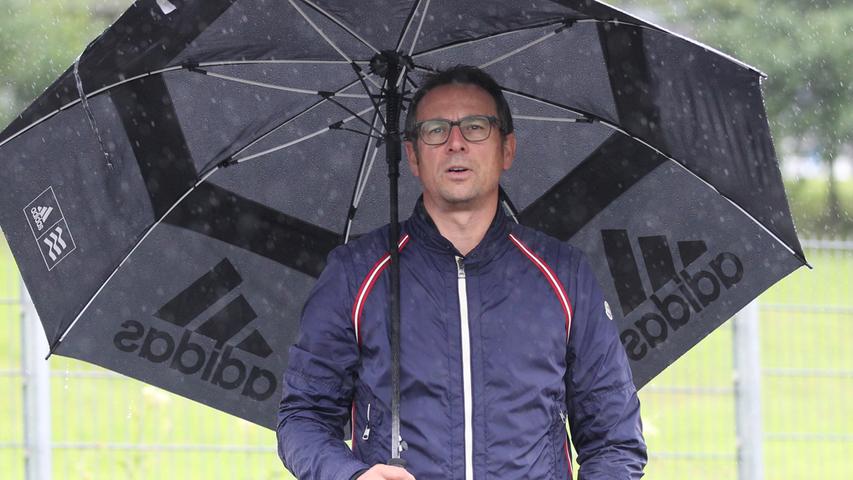 Mit dem wohl größten Regenschirm der Welt ausgestattet, beobachtet Martin Bader die Trainingseinheit der Mannschaft.
