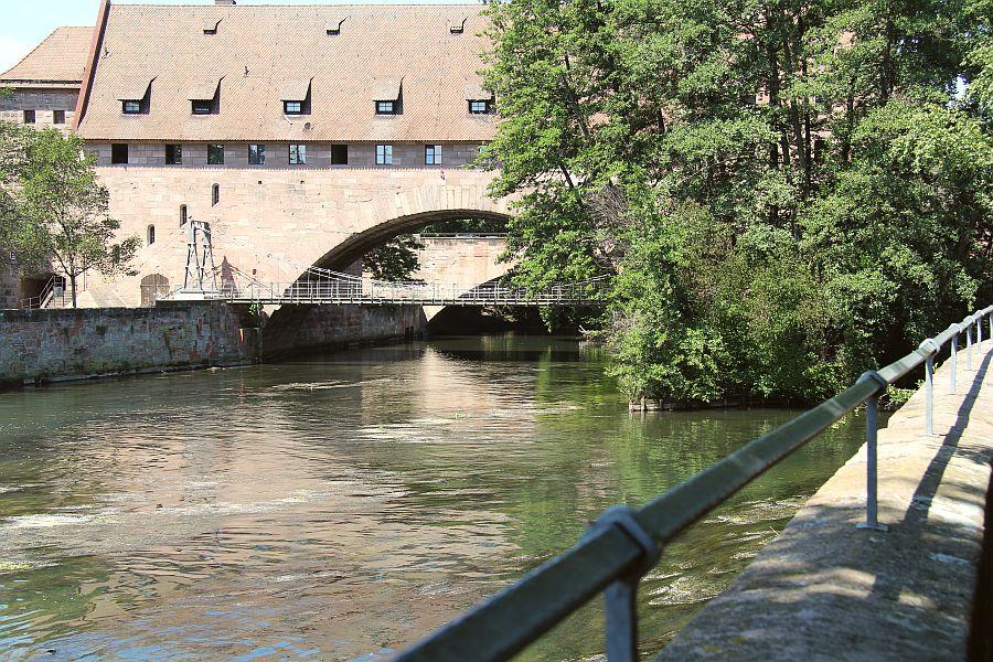 Jahrhundertelang brachte ein Holzsteg die Nürnberger über die Pegnitz. 1824 entstand dann der Kettensteg, die erste eiserne Hängebrücke auf dem europäischen Festland. Nicht nur dieser Meilenstein der Technikgeschichte, sondern auch eines der schönsten Nürnberger Biergärten an seinem nördlichen Ende, ist einen Besuch wert.