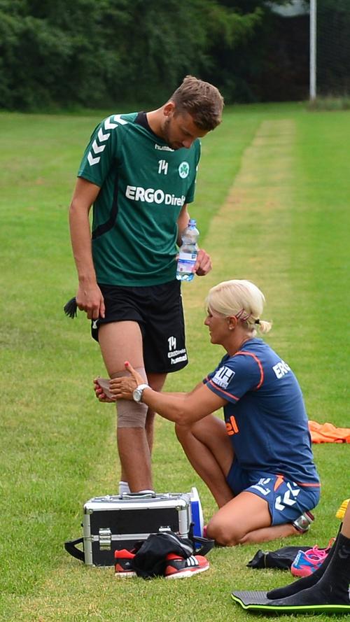Physiotherapeutin Agnieszka Tobiasz bandagiert das Knie von Tom Weilandt. Dieser nutzt die kurze Verschnaufpause und gönnt sich einen Schluck Wasser.