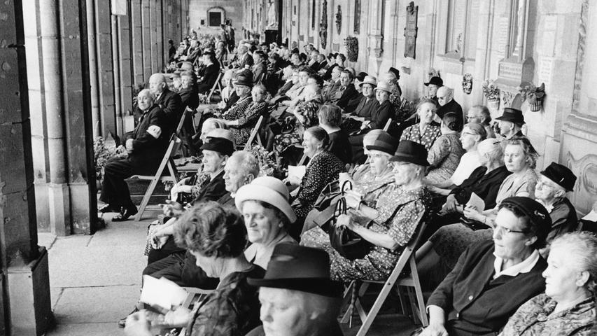 In den Arkaden des Johannisfriedhofs saßen vor Gedenkstätten viele Männer und Frauen und hörten ergriffen die Ansprache über Lautsprecher. Hier geht es zum Artikel: 1. August 1964: Mutiger Streiter für seine Kirche.