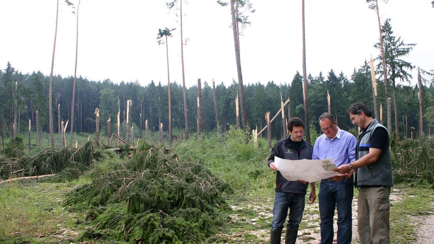 Förster Dietmar Schuster zeigt auf der Forstkarte Bürgermeister Ralf Beyer und Hans Stromberger (von rechts) von der FBG das so schwer betroffene Waldgebiet.