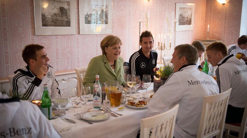 Bundeskanzlerin Angela Merkel besucht die deutsche Nationalmannschaft 2012 im Europameisterschafts-Quartier. Miroslav Klose (rechts neben Merkel) kann sich beim gemeinsamen Abendessen mit der Kanzlerin unterhalten.