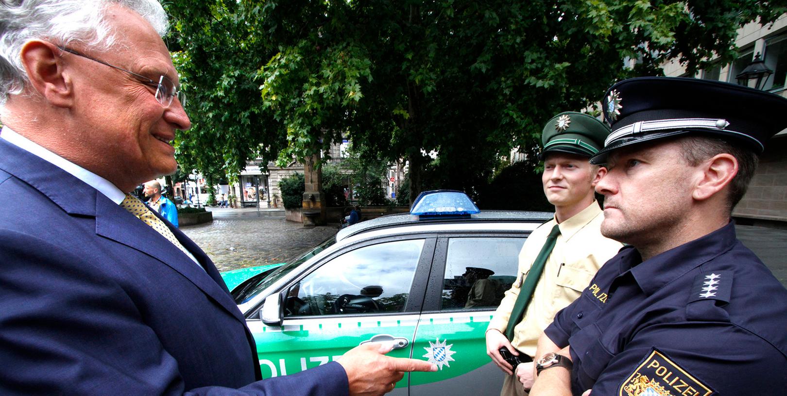 Mit Blaulicht und "rotem Flash" fahndet die Polizei in Bayern bereits - doch bei Facebook und Twitter sind die Beamten noch zurückhaltend. Innenminister Joachim Herrmann (l.) will das ändern.
